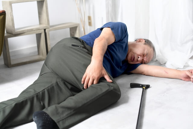 床に転んで足を痛めている老人男性