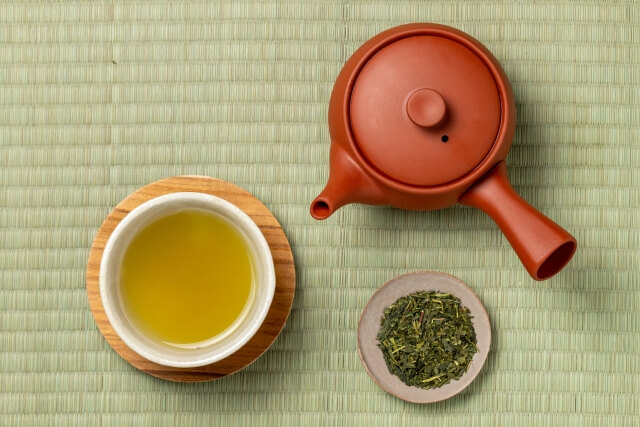 湯呑みに入った緑茶と急須と茶葉