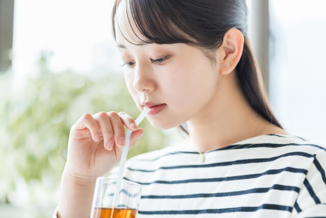 ストローで飲み物を飲む女性
