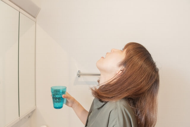 洗面所でうがいをする女性