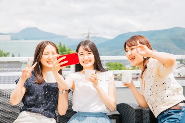 食事をしながらセルフィーをする3人の女性