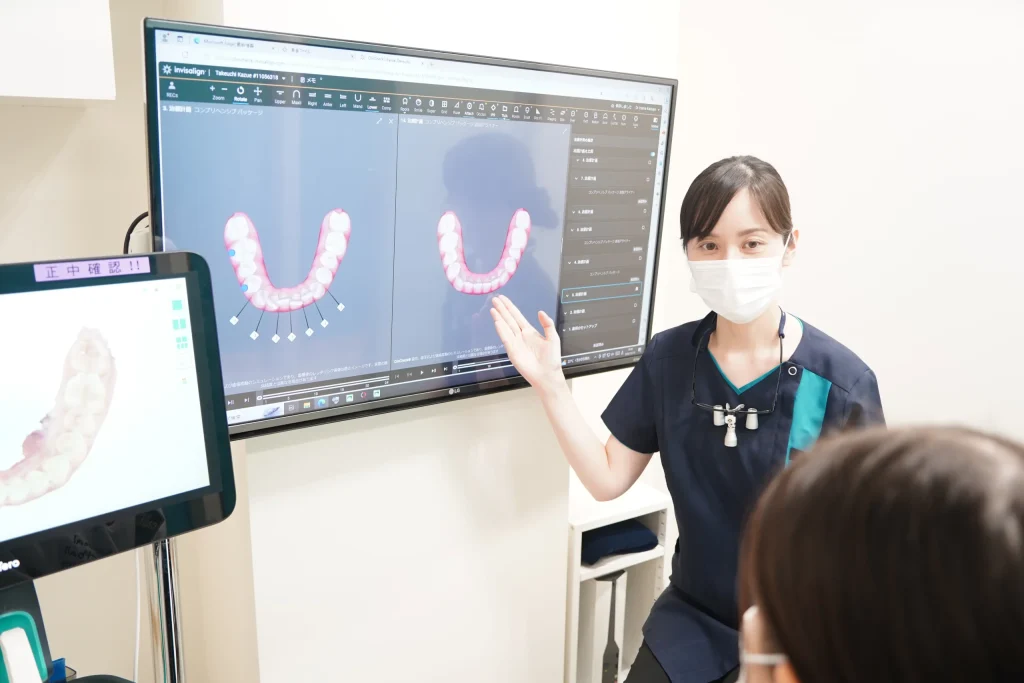 クリンチェックを使ってインビザライン矯正の治療プランについて説明する歯科医師